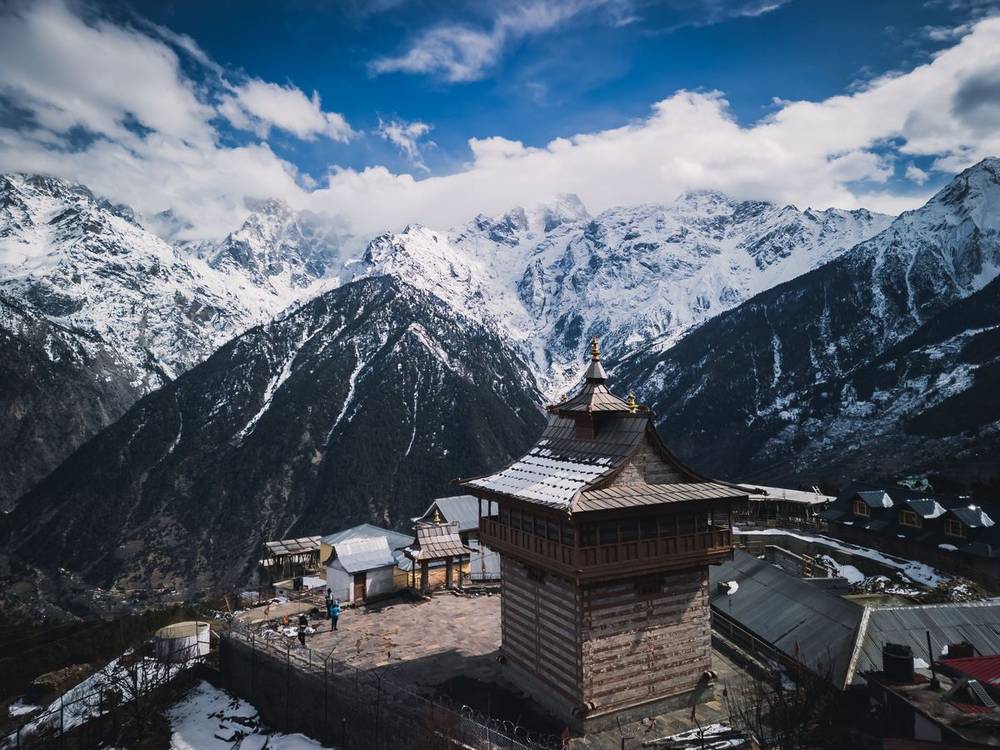 Carved wooden temple in a Kinnaur village below snow peaks